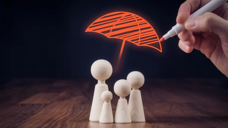 Person drawing a protective umbrella over a wooden meeple family.