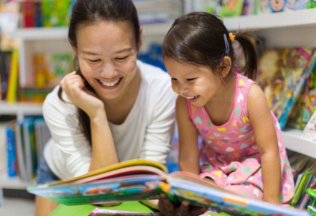 Asian mother and daughter reading books in a library.